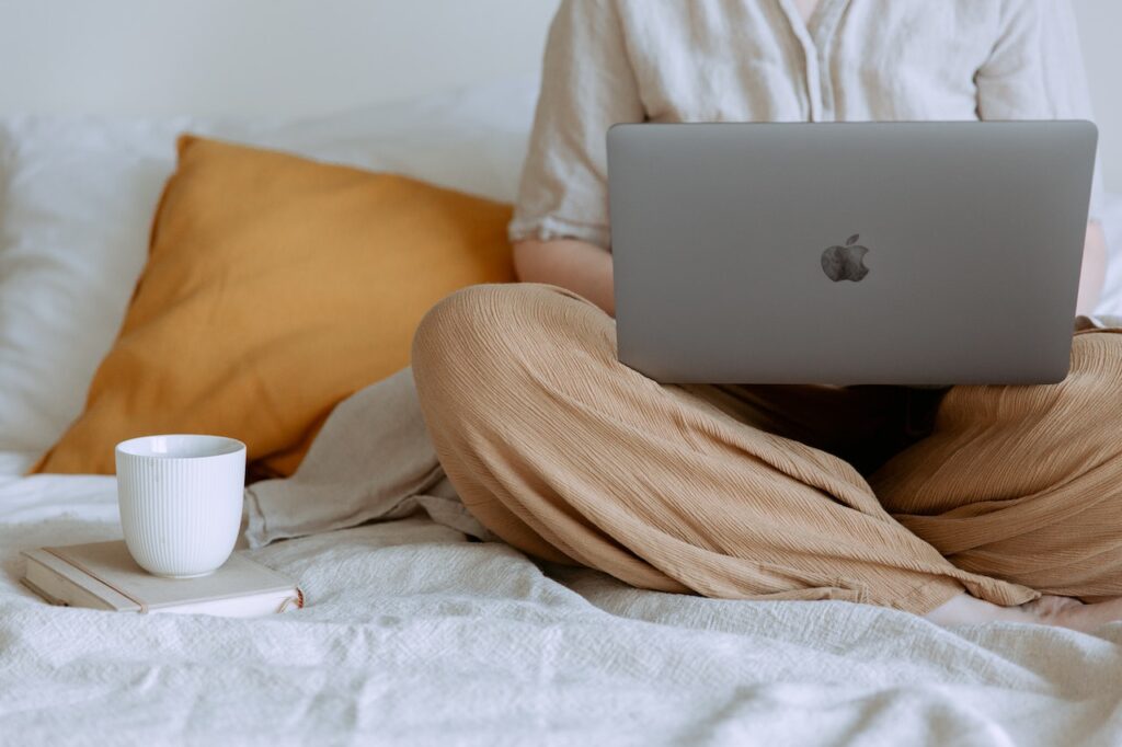 working on the bed with a laptop and coffee on the site while Finding Your Freelancing Niche